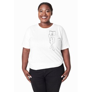 Op de afbeelding: Een wit T-shirt met een zwarte lijntekening van een persoon die zit en een boek leest.