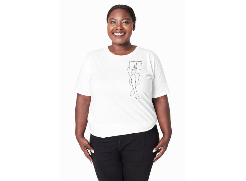 Op de afbeelding: Een wit T-shirt met een zwarte lijntekening van een persoon die zit en een boek leest.