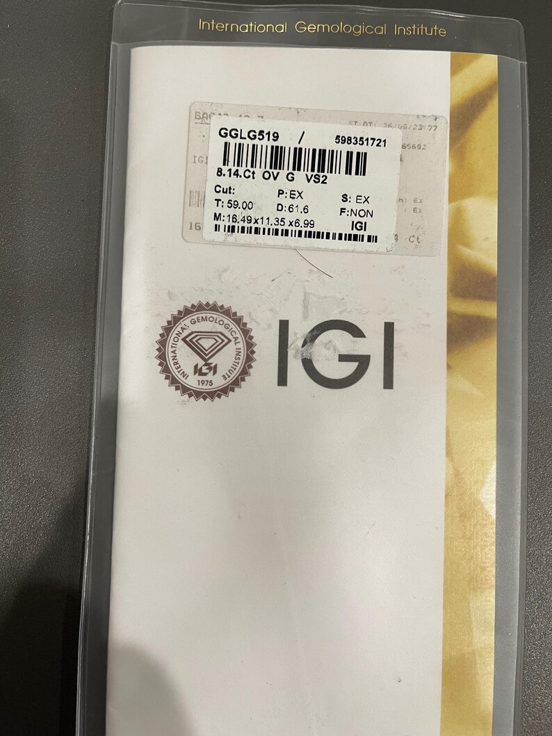 May include: A white certificate with a gold border and the text "International Gemological Institute" at the top. The certificate is for a diamond with the following information: GGLG519, 8.14 Ct, OV, G, VS2, Cut: T: 59.00, D: 61.6, M: 16.49x11.35 x6.99, P: EX, S: EX, F: NON, IGI.