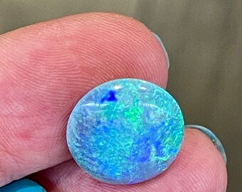 May include: A round, light blue opal gemstone with green and blue flashes of color.