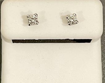 May include: A pair of small diamond stud earrings in a white jewelry box.
