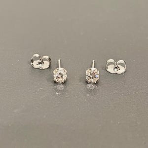 May include: A pair of silver stud earrings with clear round gemstones.