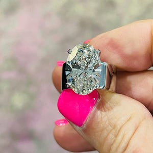 May include: A large, oval-shaped diamond ring set in a white gold band. The diamond is clear and sparkling, and the band is simple and elegant.