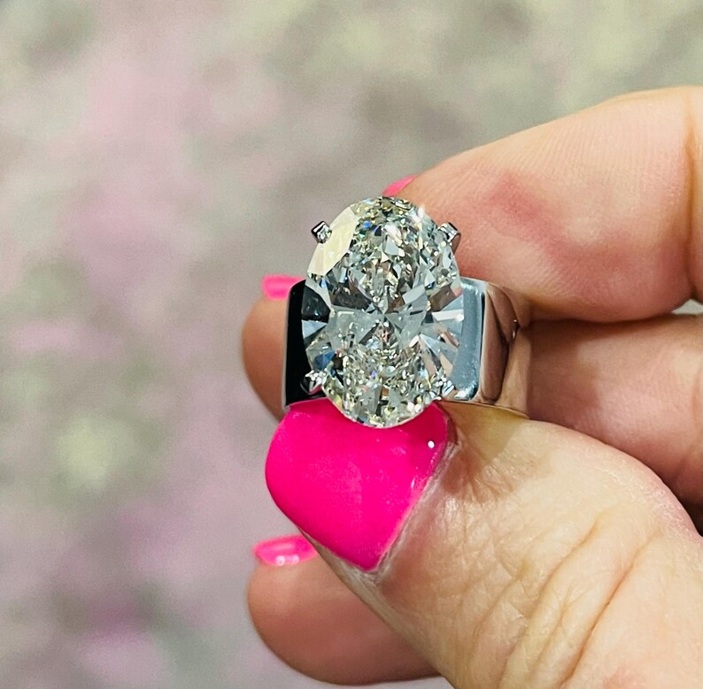 May include: A large, oval-shaped diamond ring set in a white gold band. The diamond is clear and sparkling, and the band is simple and elegant.
