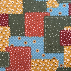 May include: A patchwork quilt design featuring squares of various patterns and colors. The quilt includes squares with white floral patterns on yellow, red polka dots, blue checkered patterns with sunflowers, and a dark green background.