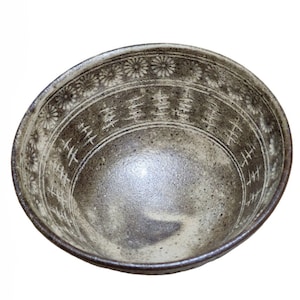 May include: A white ceramic bowl with a brown glaze and a decorative pattern of flowers and lines around the rim.
