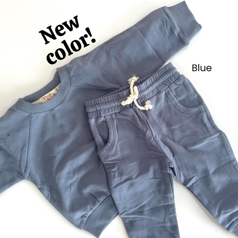 Pode incluir: Um conjunto de moletom e cal&ccedil;a de moletom azul combinando. O moletom tem gola redonda e mangas compridas. A cal&ccedil;a de moletom tem c&oacute;s el&aacute;stico com cord&atilde;o e bolsos.