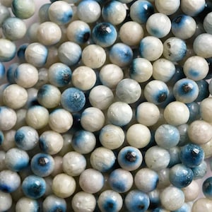 Peut inclure: Gros plan sur une collection de perles rondes blanches et bleues. Les perles ont un motif bleu et blanc marbré, ressemblant à un œil.