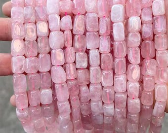 Puede incluir: Un hilo de cuentas de cuarzo rosa. Las cuentas son rectangulares con bordes redondeados y un suave tono rosado. Las cuentas están ensartadas con hilo rosa, creando una línea continua de piedras preciosas. Las cuentas son lisas y pulidas, reflejando la luz.