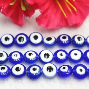 Puede incluir: Una hebra de cuentas de vidrio azul con dise&ntilde;os de ojo turco blanco. Las cuentas son redondas y tienen un acabado brillante.