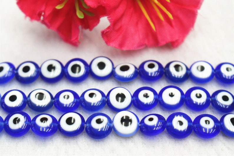 Puede incluir: Una hebra de cuentas de vidrio azul con dise&ntilde;os de ojo turco blanco. Las cuentas son redondas y tienen un acabado brillante.