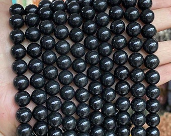May include: A strand of black obsidian beads, each bead is round and smooth. The beads are arranged in a symmetrical pattern, creating a visually appealing design.