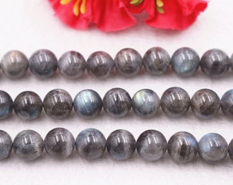 May include: A strand of round, dark gray labradorite beads with iridescent flashes of blue and green. The beads are arranged in three rows.