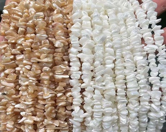 Puede incluir: Dos hebras de cuentas de concha plana, de forma irregular e iridiscente. Una hebra es de color marrón claro y la otra es blanca.