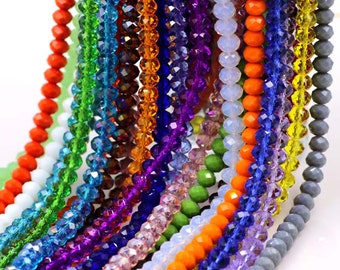 May include: A collection of colorful faceted glass beads in various shades of blue, green, purple, orange, and white. The beads are arranged in rows, creating a visually appealing display.
