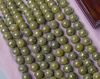 May include: A strand of green serpentine beads, each bead is round and has a speckled texture.