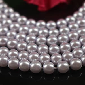 May include: A strand of light purple pearl beads. The beads are round and smooth, and they are strung on a clear thread.