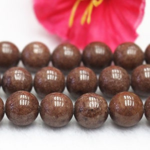 May include: A strand of brown gemstone beads. The beads are round and have a speckled appearance.