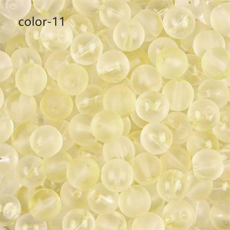 May include: A close-up image of a large quantity of translucent, pale yellow beads. The beads are round and smooth, with a slight shimmer.