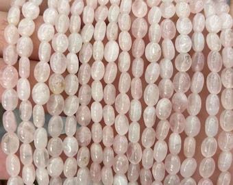 May include: Strands of oval-shaped, pale pink rose quartz beads. The beads are strung together, displaying a soft, translucent appearance. The beads are a light pink color, and are smooth and polished.