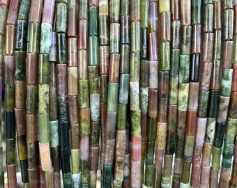 May include: A close-up view of strands of gemstone beads. The beads are cylindrical and feature a mix of colors, including green, brown, pink, and beige. The beads are strung together, creating a textured and colorful pattern.