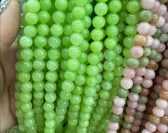 Puede incluir: Una hebra de cuentas redondas de color verde claro. Las cuentas son lisas y tienen una apariencia ligeramente translúcida.