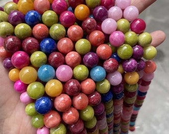 Puede incluir: Una hebra de cuentas redondas de colores hechas de piedra pulida. Las cuentas son de varios tonos de verde, azul, rosa, rojo, amarillo y naranja.