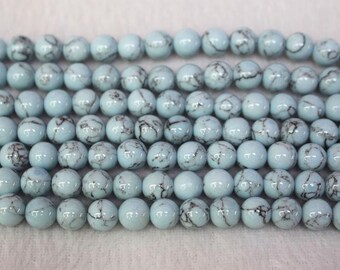 May include: A strand of light blue round beads with black marbling. The beads are approximately 10mm in diameter.