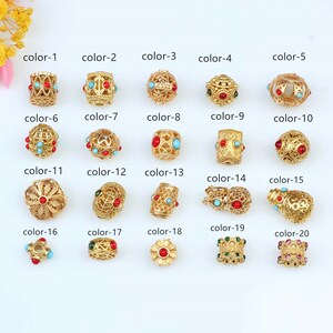 May include: Twenty gold-colored beads with various designs and colored stones. The beads are arranged in rows with labels indicating their color number.