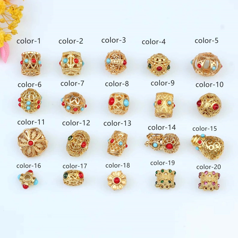 May include: Twenty gold-colored beads with various designs and colored stones. The beads are arranged in rows with labels indicating their color number.