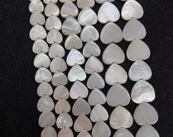 May include: A strand of white heart-shaped shell beads. The beads have a pearlescent finish and are arranged in rows.