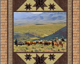 May include: A brown and tan quilt with a rope border and a barbed wire design. The center of the quilt features a landscape scene with a herd of cattle and two cowboys on horseback. The quilt is decorated with brown stars with a tan background.