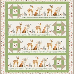 May include: A green and brown quilt with a repeating pattern of deer, foxes, bunnies, and mushrooms. The quilt has a white background with a green border and a brown border with a floral pattern. The quilt has a sign that says "Hello World" on it.