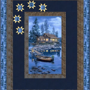 May include: A framed print of a cabin in the woods by a lake at night. The cabin has lights on in the windows and a small boat is docked at the shore. The print is surrounded by a dark blue frame with a gold star pattern in the corners.