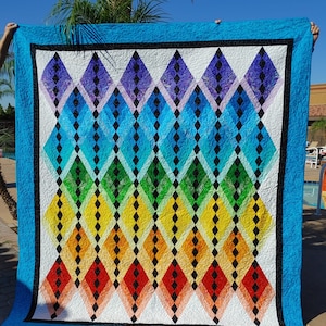 May include: A colorful quilt with a diamond pattern in shades of blue, green, yellow, orange, and red. The quilt is bordered in black and blue fabric.