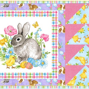 May include: A white fabric panel with a pink, blue, and green plaid border. The center features a gray bunny rabbit with a yellow chick and colorful Easter eggs. The right side of the panel has a pink background with three blue triangles, each with a yellow chick pattern.