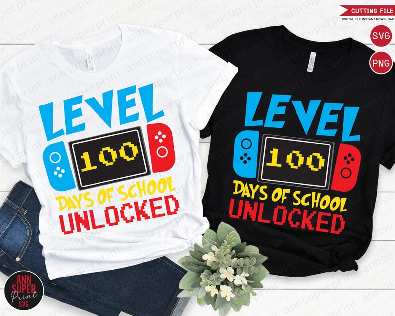 Op de afbeelding: Twee T-shirts met een videogameontwerp. Het witte T-shirt heeft blauwe en rode accenten, terwijl het zwarte T-shirt rode en blauwe accenten heeft. Beide T-shirts tonen de tekst "Level 100 Dagen School Ontgrendeld".
