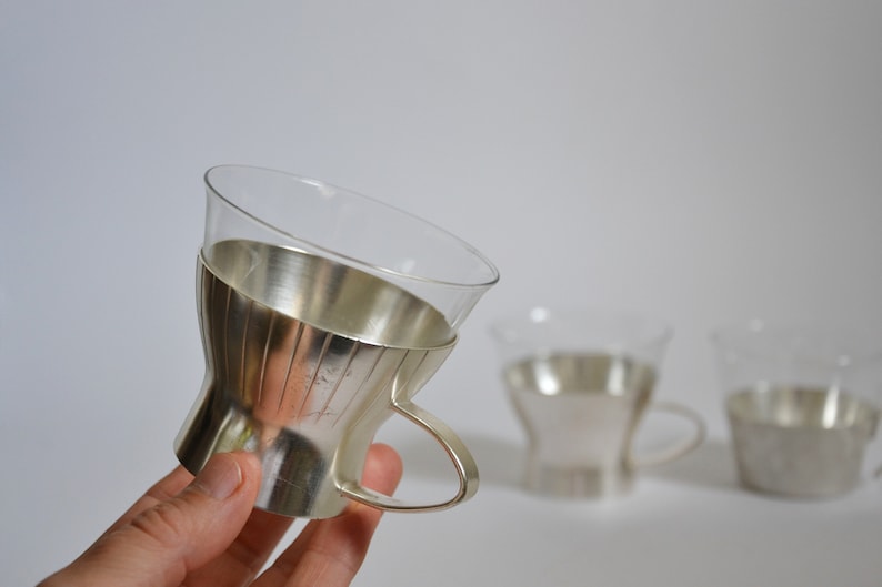 Peut inclure: Ensemble de trois tasses en verre plaqu&eacute; argent avec un motif cannel&eacute;. Les tasses ont un corps en verre transparent et un bord et une poign&eacute;e plaqu&eacute;s argent.