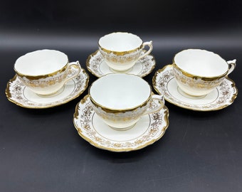 May include: Set of four white teacups and saucers with gold trim and floral patterns.