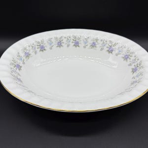 May include: A white oval serving bowl with a gold rim and a delicate floral pattern in shades of purple and green.