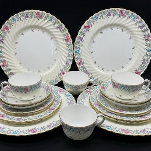 May include: A set of six vintage floral teacups and saucers. The cups and saucers are white with a delicate floral pattern in shades of pink, purple, and green. The set includes two teacups and saucers, two teacups and saucers, and two saucers.