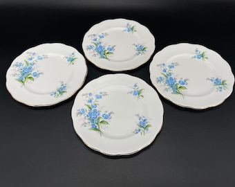 May include: Set of four white porcelain plates with a blue and green floral design. The plates have a gold rim and are perfect for serving desserts or appetizers.