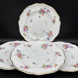 May include: Four white ceramic plates with a gold rim and a floral pattern in shades of pink, blue, and green.