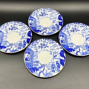 May include: Set of four blue and white porcelain teacups with a gold rim. Each cup features a detailed floral design with a pagoda and figures in the centre.