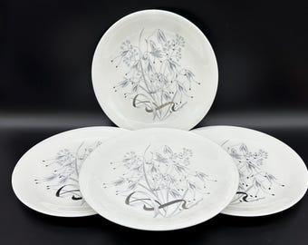 May include: Set of four white ceramic dinner plates with a gray floral design. The plates feature a stylized floral pattern with delicate gray leaves and flowers.
