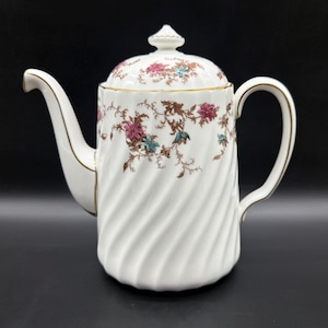 May include: White porcelain teapot with a spiral design and floral pattern in pink, teal, and brown. The teapot has a lid with a small finial and gold trim. A classic piece for serving tea.