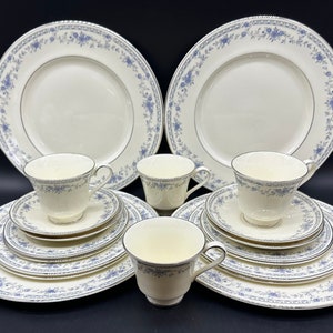 Può includere: Un set di stoviglie in porcellana bianca con un motivo floreale blu. Il set comprende piatti fondi, piatti piani, tazze e piattini.