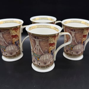 May include: Four white ceramic mugs with handles, featuring a design of a human figure, a dome, and text around the rim. The mugs have a gold rim and a white base. The background of the design is a mix of brown and beige.