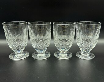 May include: Four clear glass tumblers with a cut glass design. The glasses have a round base and a wide mouth.