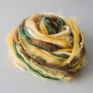 May include: A ball of yarn with a mix of brown, yellow, green, and white threads.